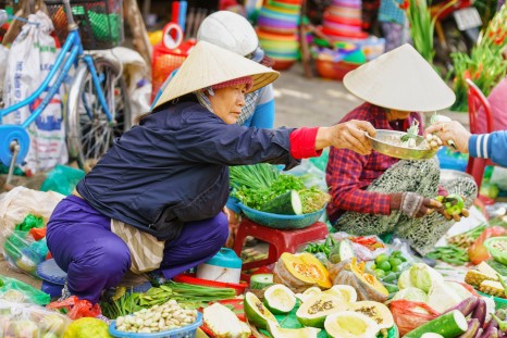 Hoi An, Vietnam - February 17, 2016: Asian woman in traditional vietnamese hats selling fresh vegetables in the street market in Hoi An, Vietnam.