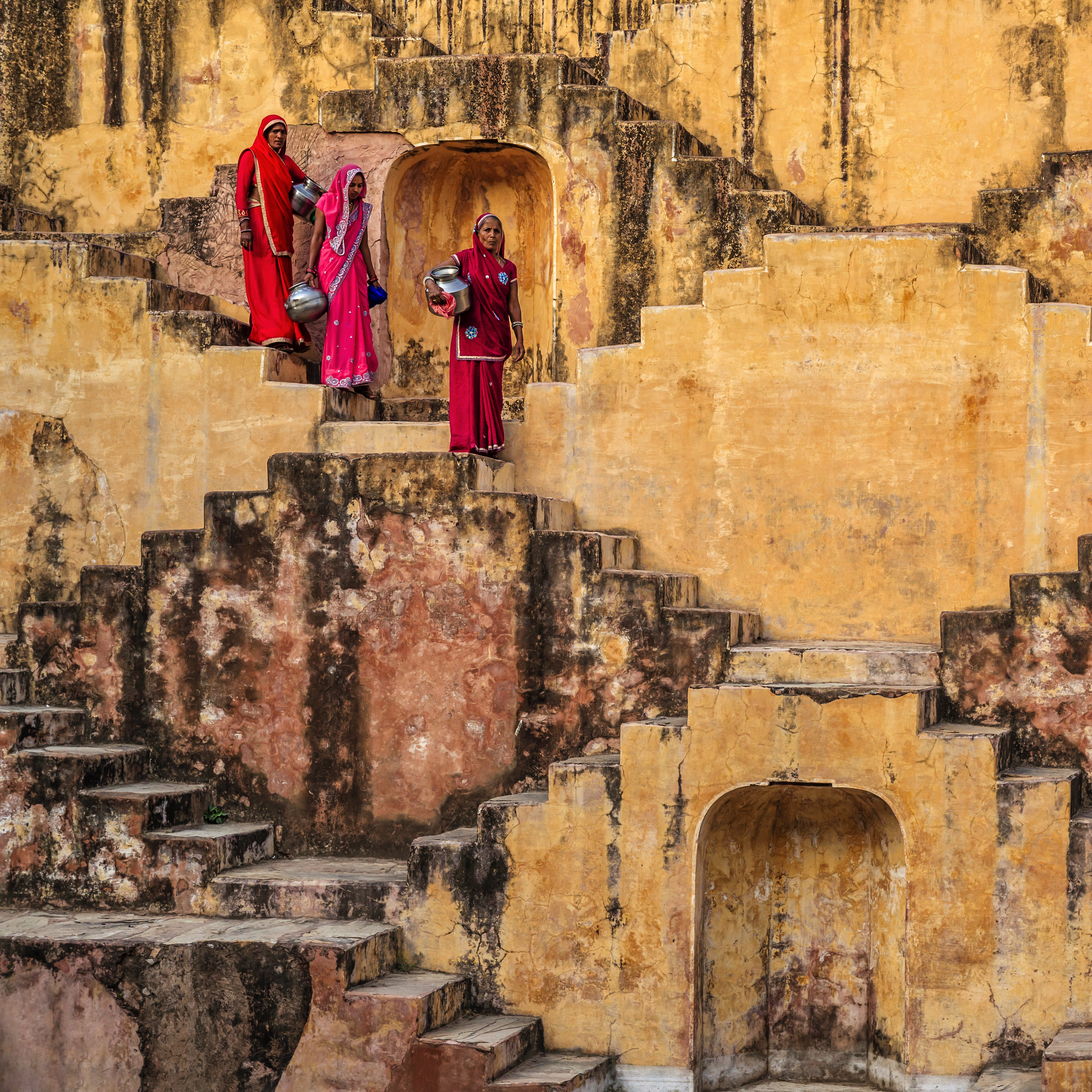 Indian women carrying water from stepwell near Jaipur, Rajasthan, India. Women and children often walk long distances to bring back jugs of water that they carry on their head.