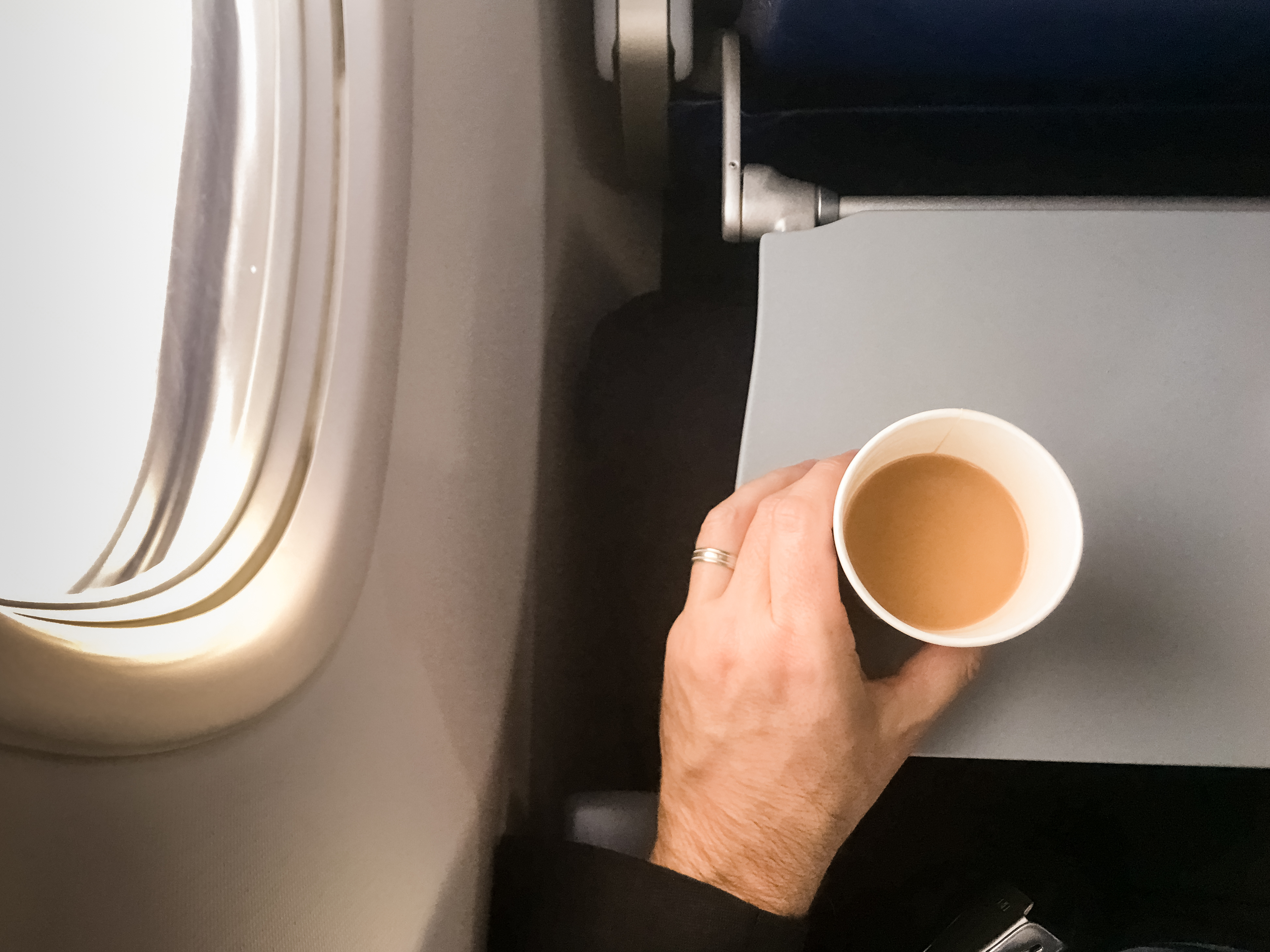 Male passenger holding a cup of coffee in aircraft