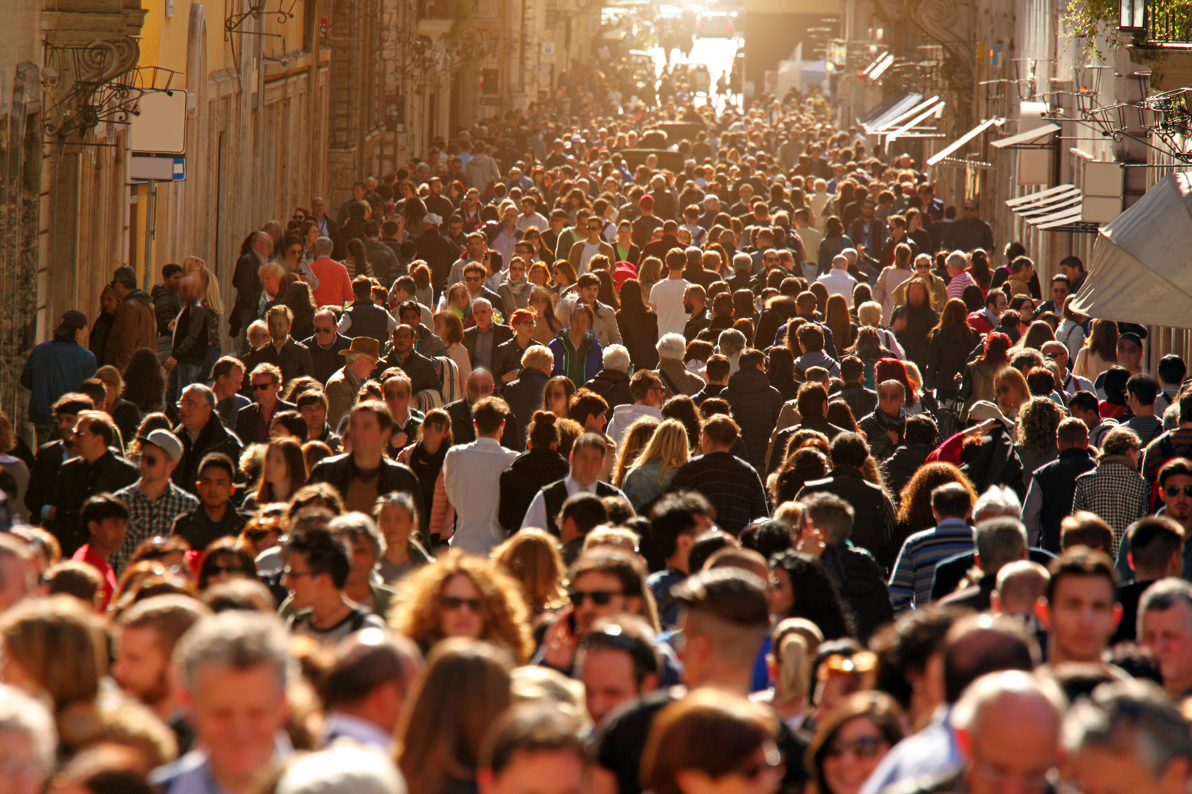 Crowd of people walking on street in downtown Rome, sunlight