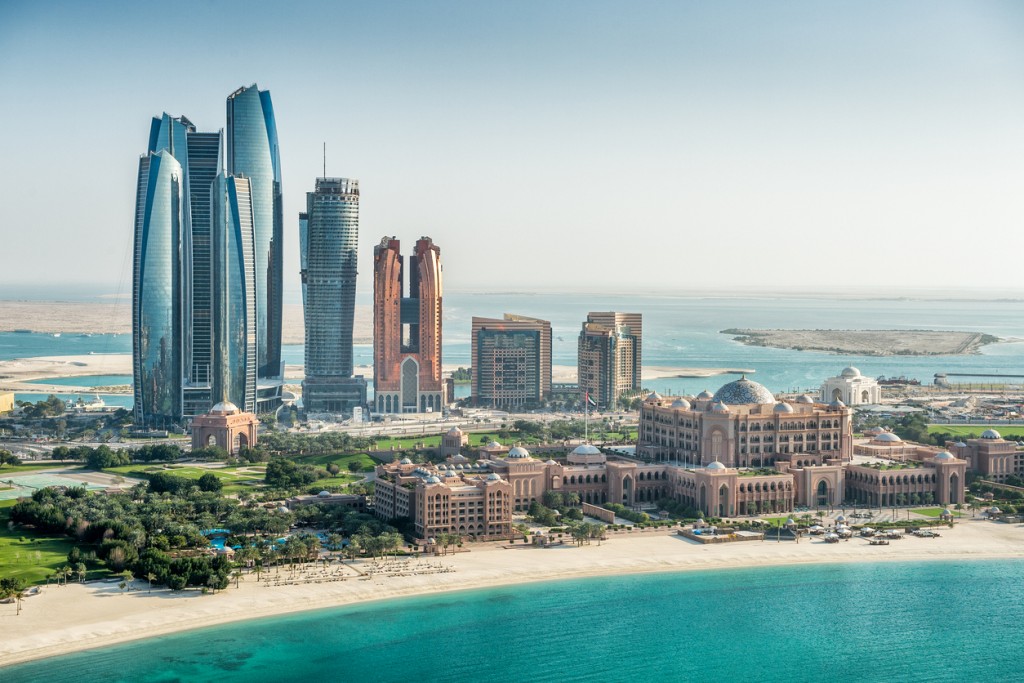 Helicopter point of view of sea and skyscrapers in Corniche bay in Abu Dhabi, UAE. Turquoise water and blue sky combined with building exterior.