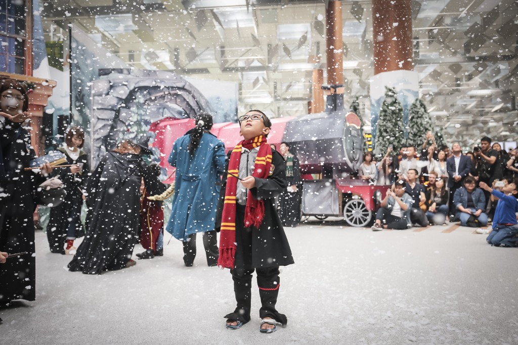 A young fan entralled by the snow at a wintry Hogsmeade Village-inspired setup at Terminal 3 Departure Hall