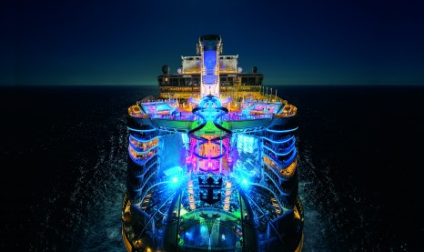HM, Harmony of the Seas, OOH, night, nighttime drone shot, aerial of ship, aft, rear view, colorful lights, Ultimate Abyss in center, top pool decks,