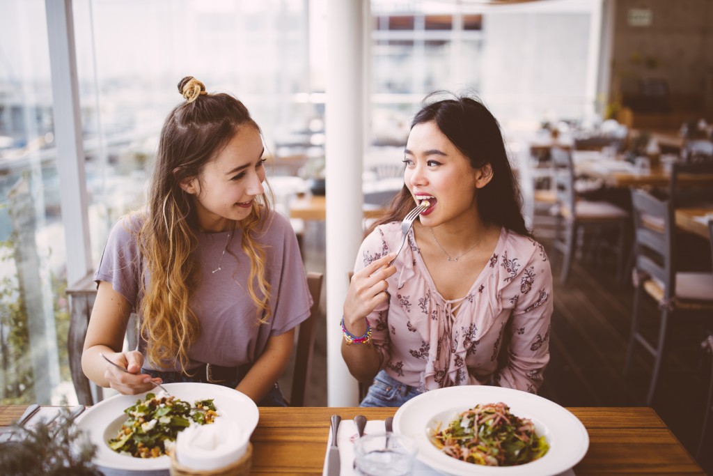 Multi-ethnic female hipster friends having lunch together at Italian restaurant