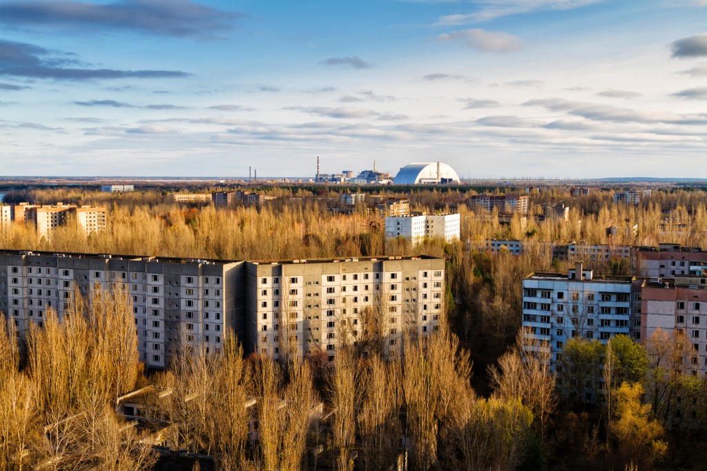 A view over Chernobyl, with a view of the white, dome-like New Safe Confinement (NSC) structure in the distance.