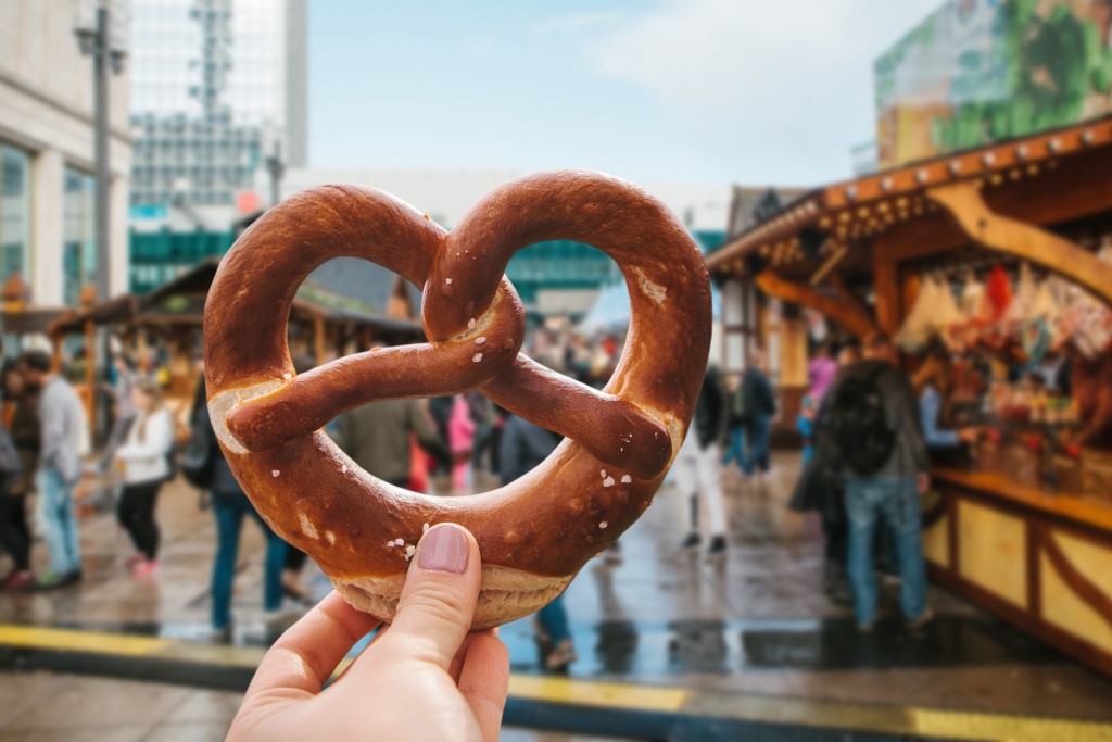 A girl or a young woman is holding a traditional German pretzel