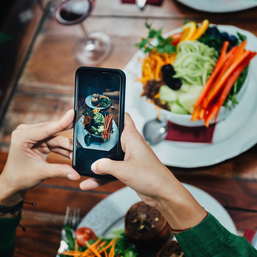 Girl Photographing Food In A Restaurant