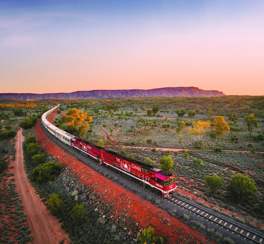 Rail Europe The Ghan heading north Alice Springs at sunset. MacDonnell Ranges in ...